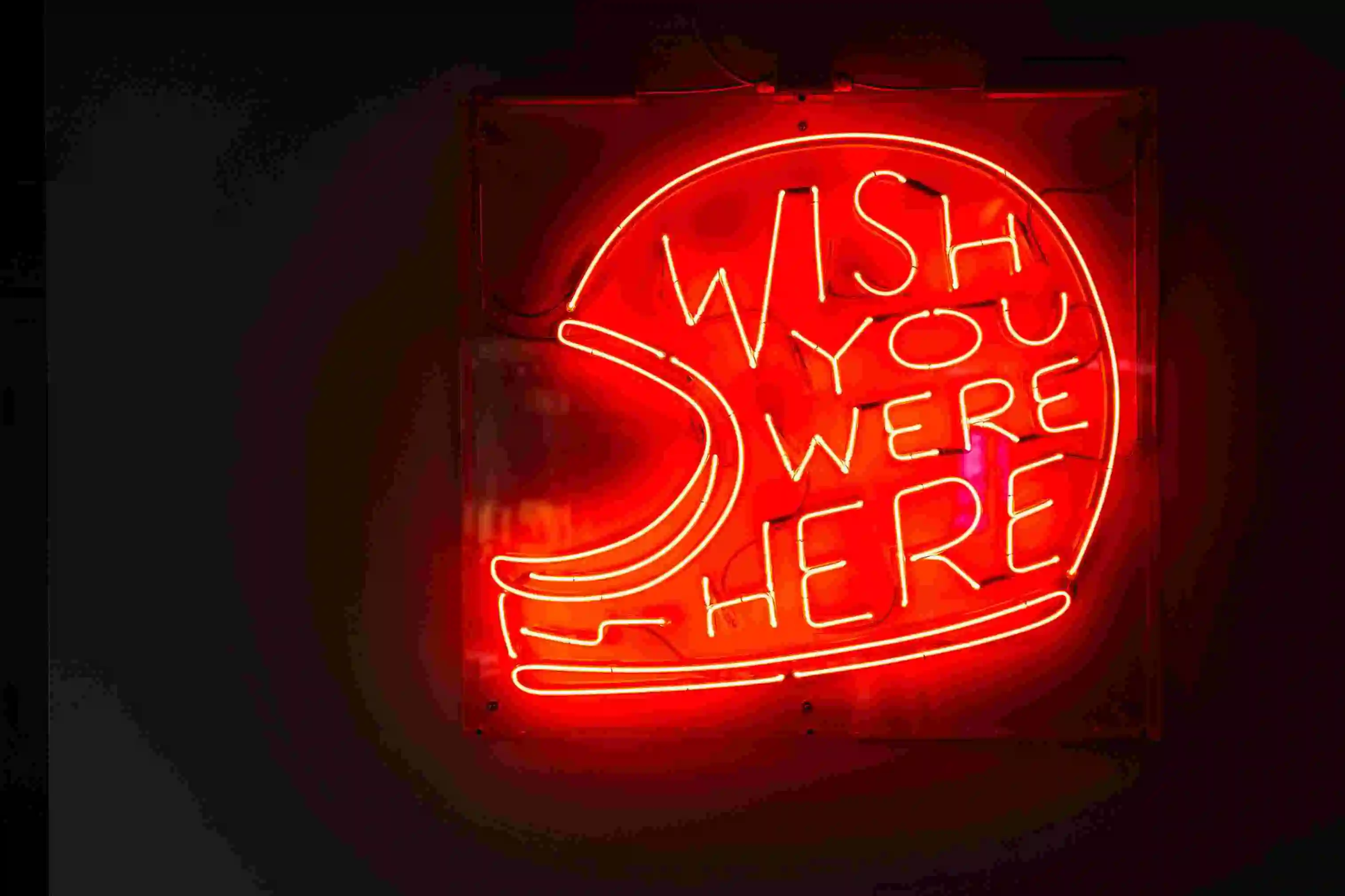 letreiro neon no formato de um capacete com as palavras 'wish you were here'